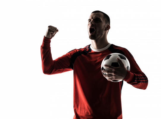 homem de camiseta vermelha comemorando segurando uma bola de futebol preta e branca nos braços