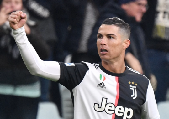 Cristiano Ronaldo usando uniforme preto e branco levantando o braço direito em sinal de comemoração