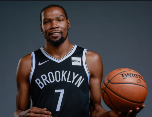 kevin durant usando uniforme preto com as escritas brooklyn e segurando uma bola de basquete laranja