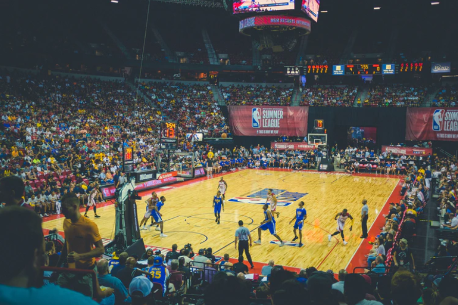 quadra de basquete com jogadores do esporte e arquibancadas lotadas com torcedores